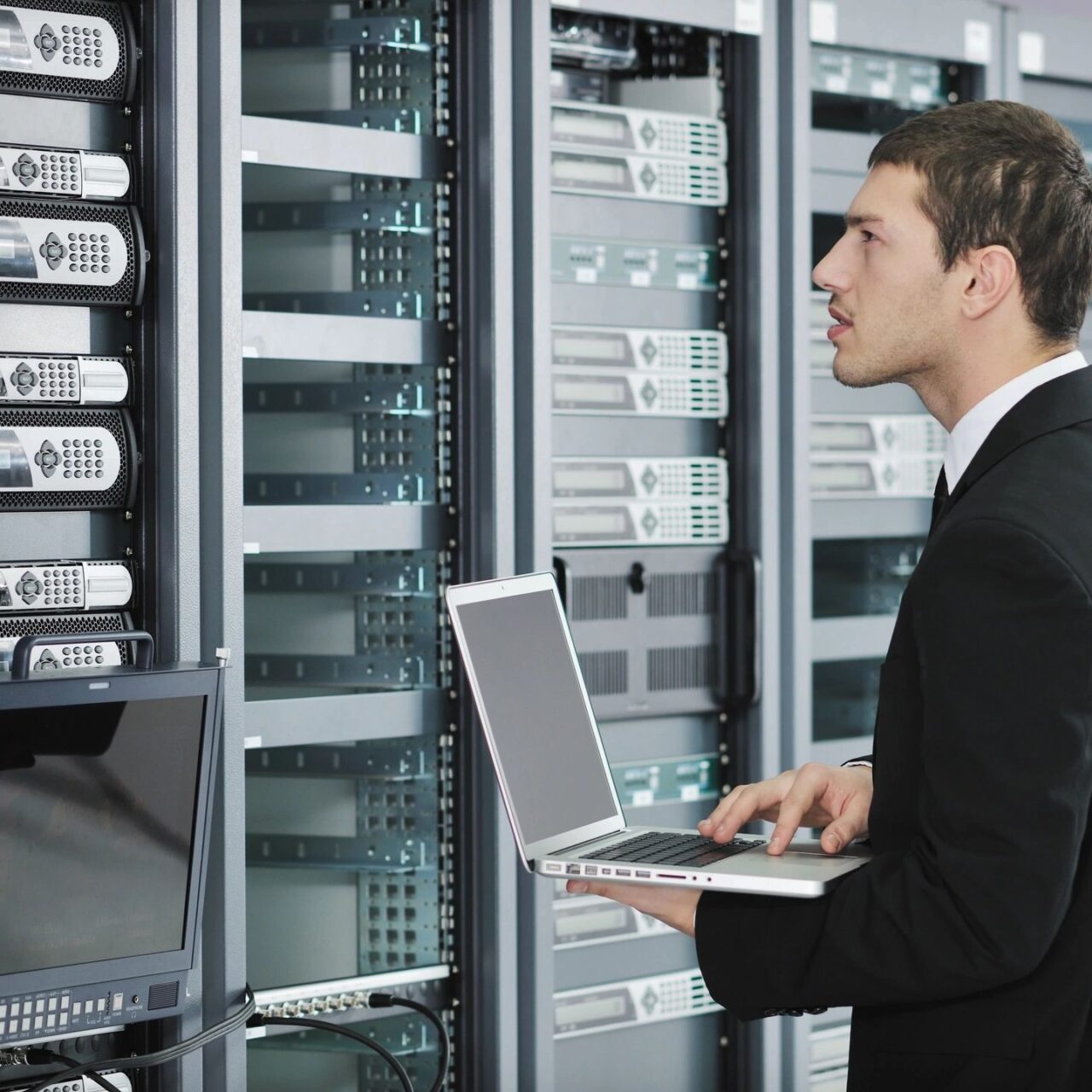 Businessman with Laptop in Network Server Room